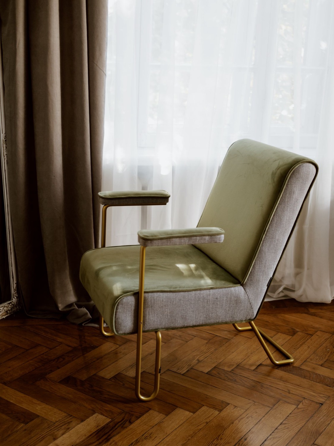 Green upholstered armchair by a window