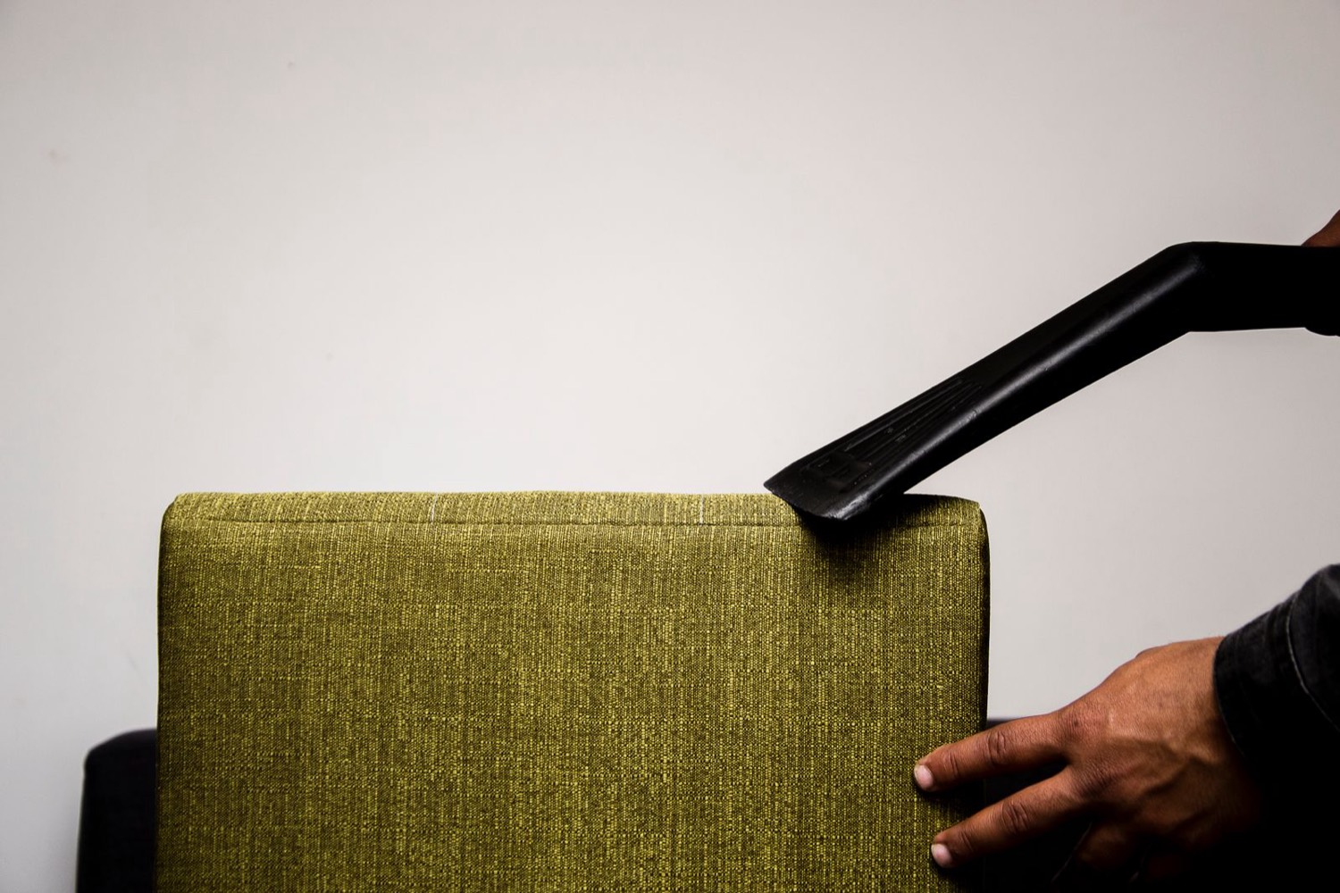 Upholstery tool cleaning a green cushion