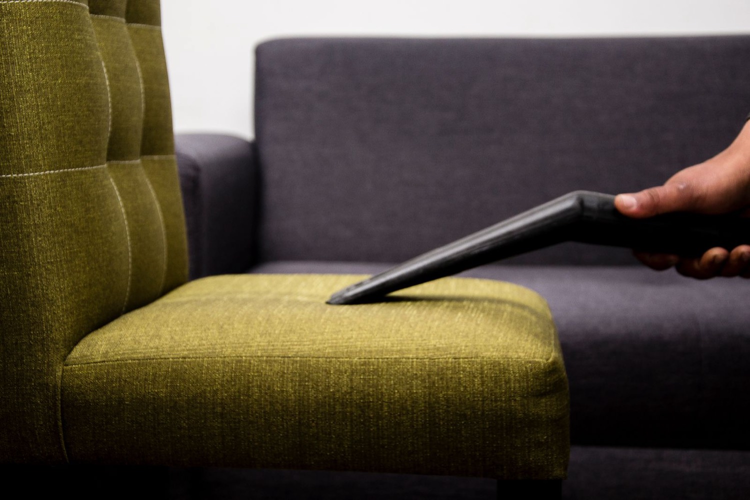 Technician cleaning a fabric sofa cushion with an upholstery extraction tool